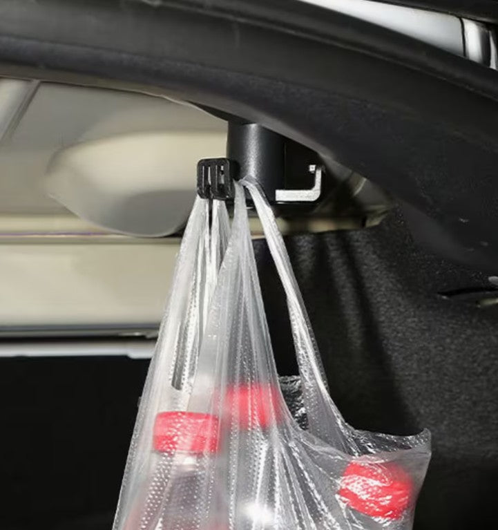 A black plastic car trunk hook holding a clear plastic shopping bag with red-capped bottles inside a car trunk. tesla-model-3-highland-grocery-shopping-bag-trunk-hook-1-piece-teslary-dublin-ireland-nederlands-deutscgland-espana-alicante-madrid-tesla-shop-europe-france-ita-292655